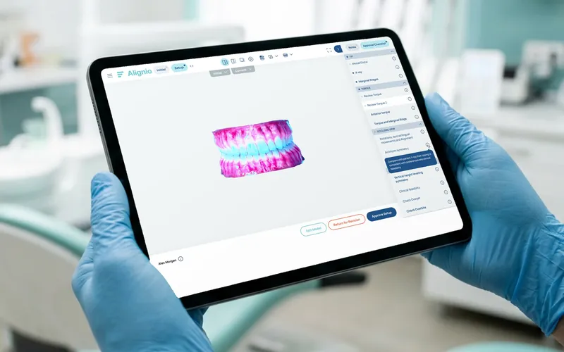 Alignio 3D dental plan review on a tablet held in gloved hands